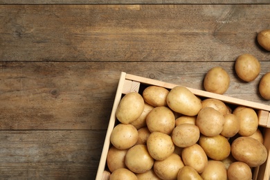 Photo of Raw fresh organic potatoes on wooden background, top view. Space for text