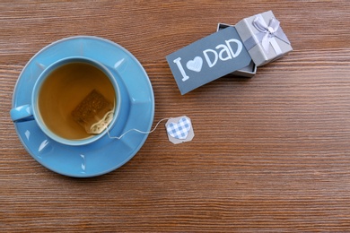 Photo of Cup of tea and gift box on wooden background. Father's day celebration