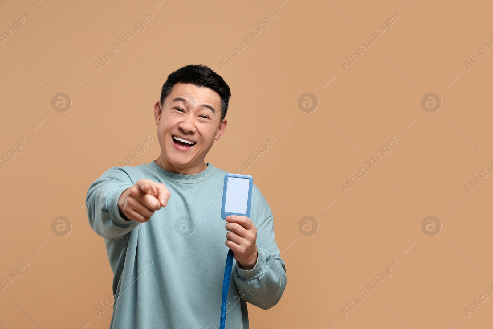 Photo of Happy asian man with vip pass badge on beige background. Space for text