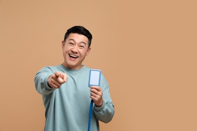 Photo of Happy asian man with vip pass badge on beige background. Space for text