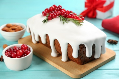 Traditional classic Christmas cake decorated with cranberries and rosemary on turquoise wooden table