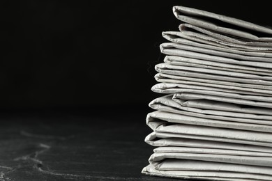 Photo of Stack of newspapers on dark stone table, space for text. Journalist's work