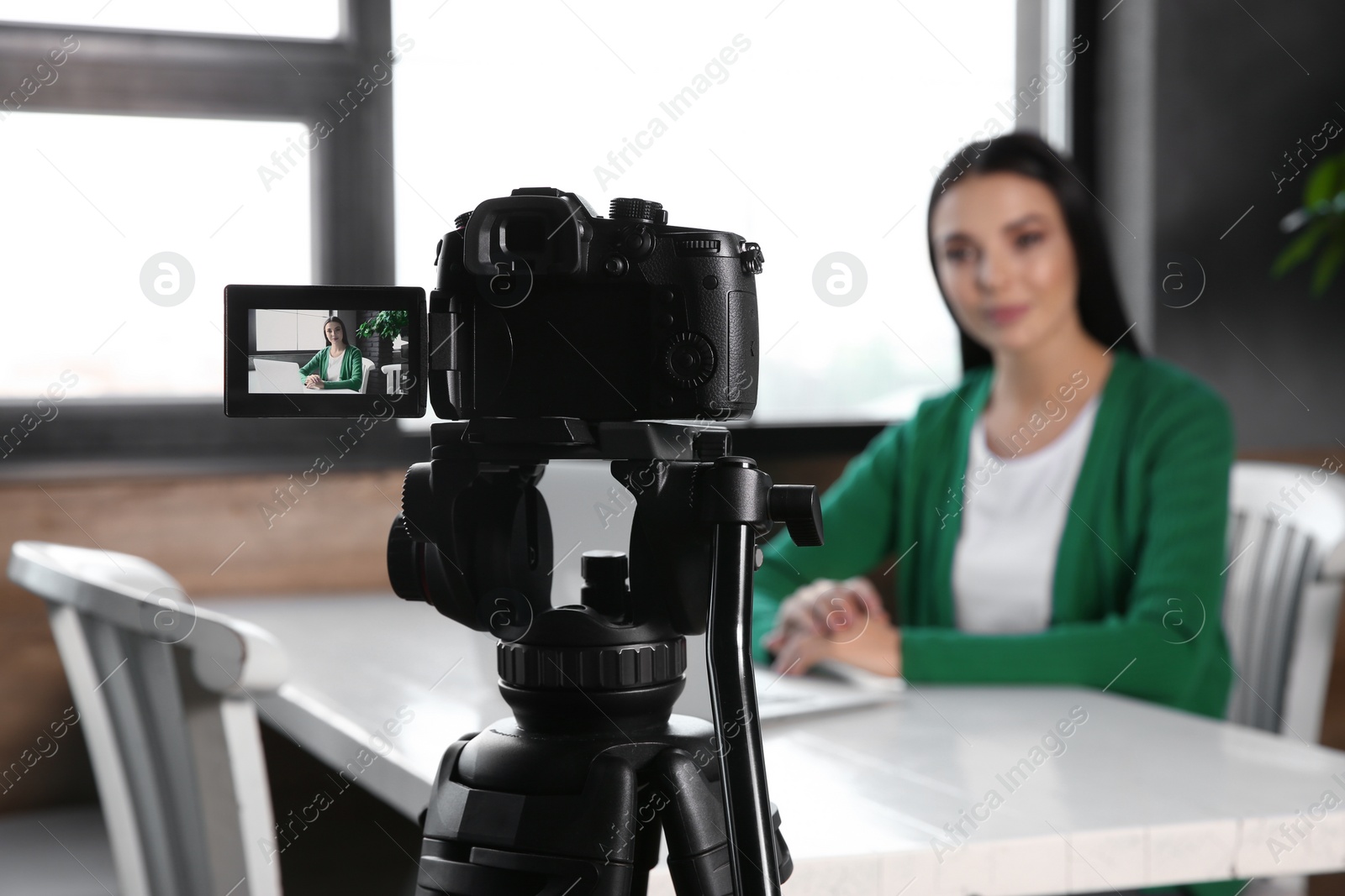 Photo of Young blogger with laptop recording video at cafe, focus on camera screen