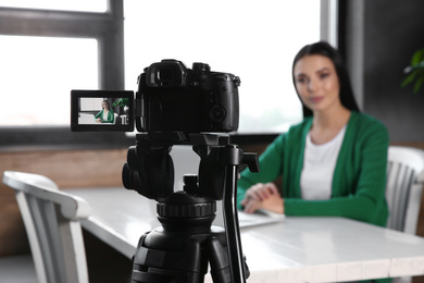 Young blogger with laptop recording video at cafe, focus on camera screen