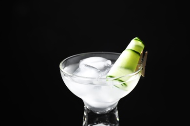 Photo of Glass of delicious cucumber martini with ice on dark background