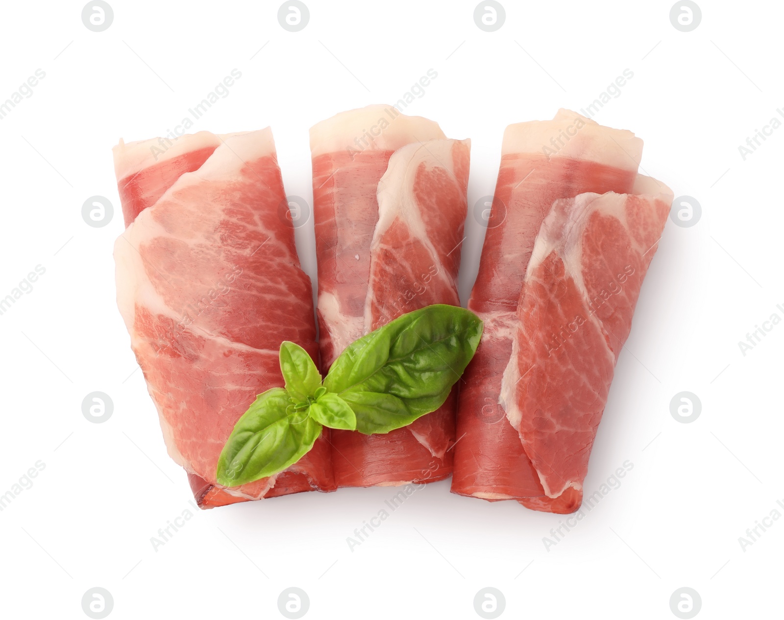 Photo of Rolled slices of delicious jamon and basil leaves isolated on white, top view