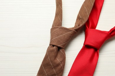 Photo of Two neckties on white wooden table, top view. Space for text