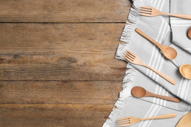 Grey cloth, spoons and forks on wooden table, flat lay with space for text. Cooking utensils