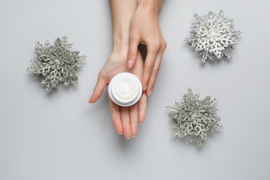 Photo of Woman with jar of hand cream on light grey background, top view