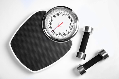 Photo of Modern scales and dumbbells on white background, top view