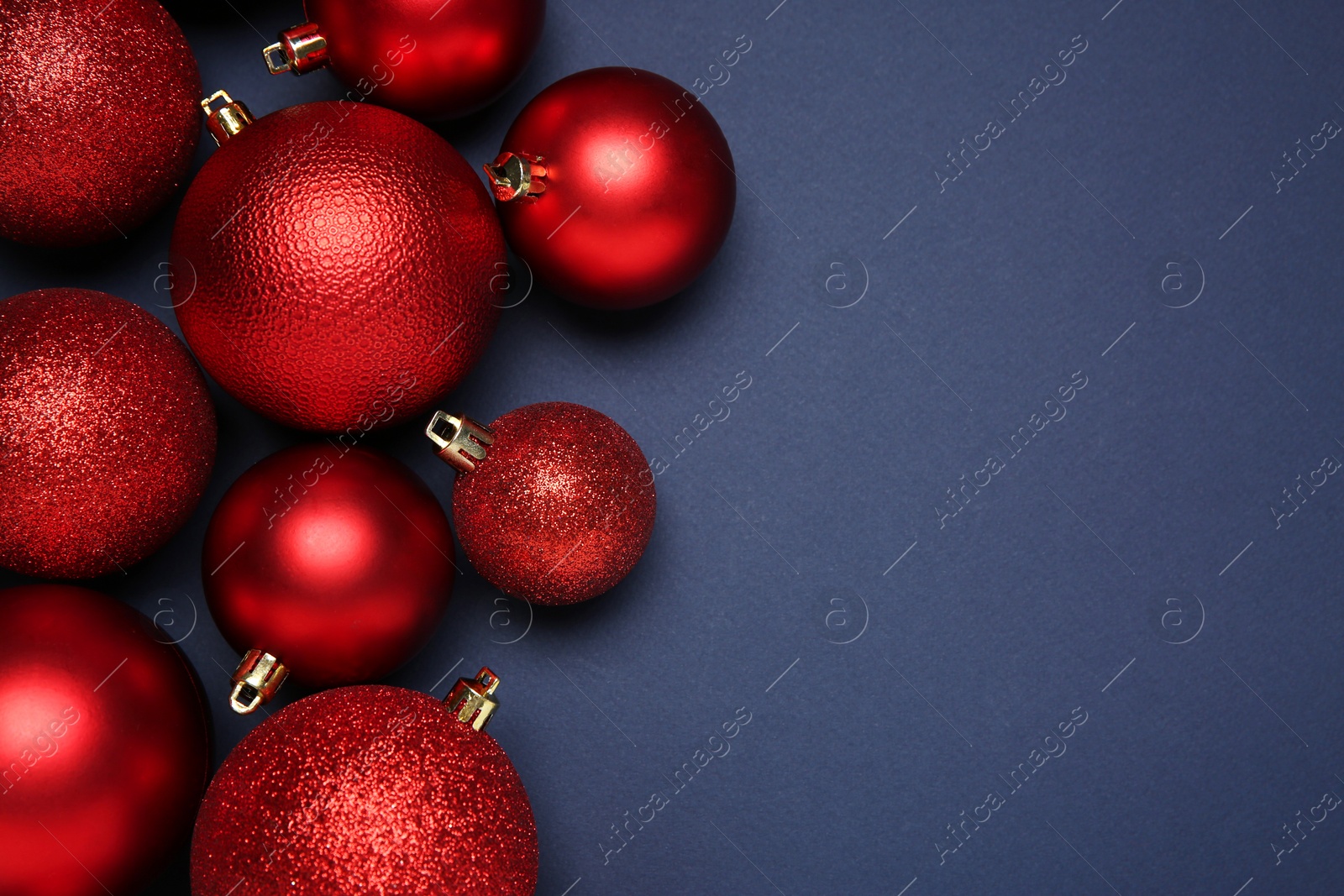 Photo of Red Christmas balls on dark blue background, top view. Space for text