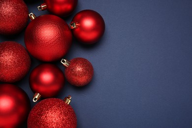 Red Christmas balls on dark blue background, top view. Space for text