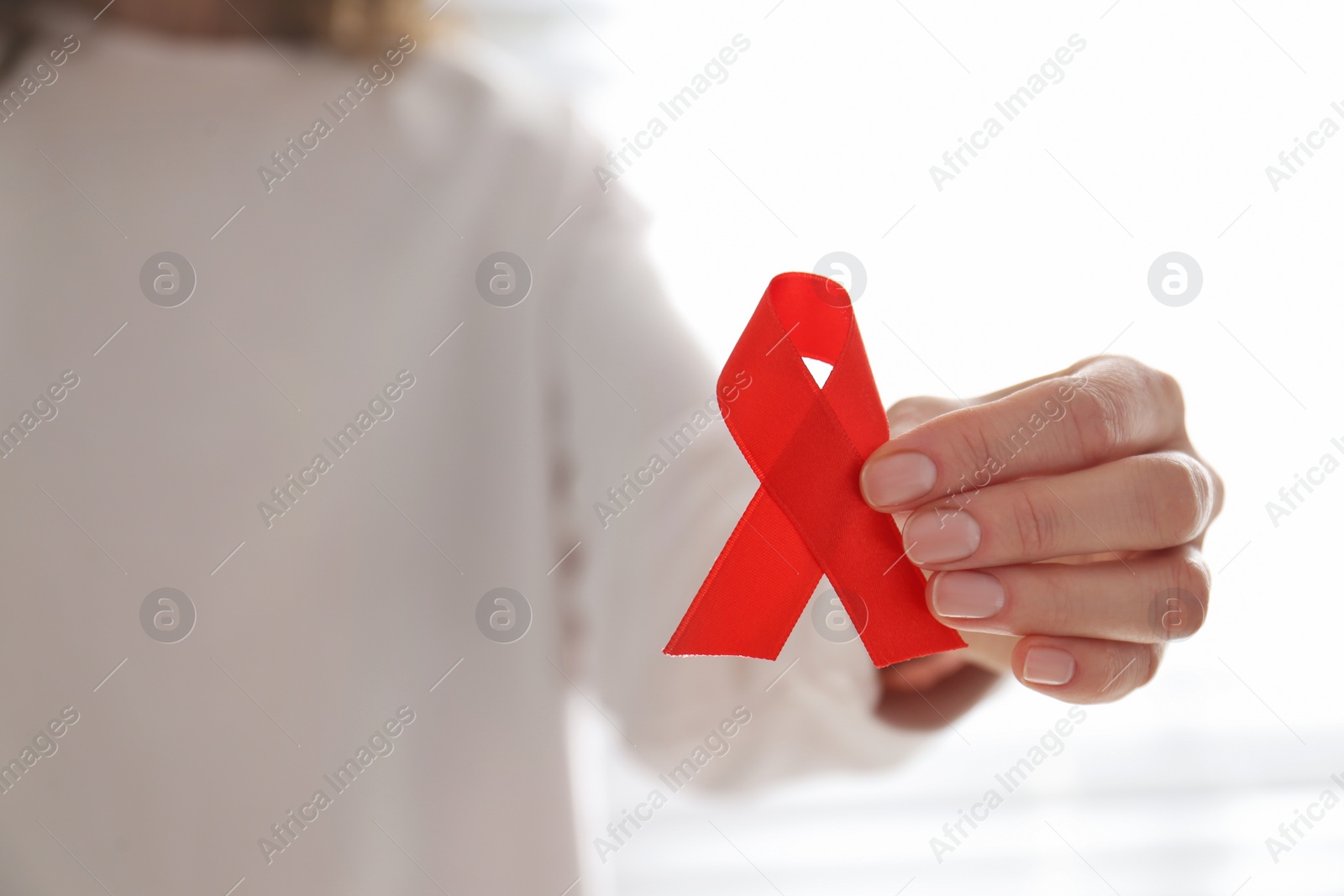 Photo of Woman holding red awareness ribbon, closeup with space for text. World AIDS disease day