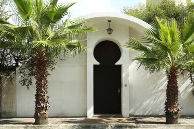 Photo of Entrance of building with beautiful door and palm trees outdoors