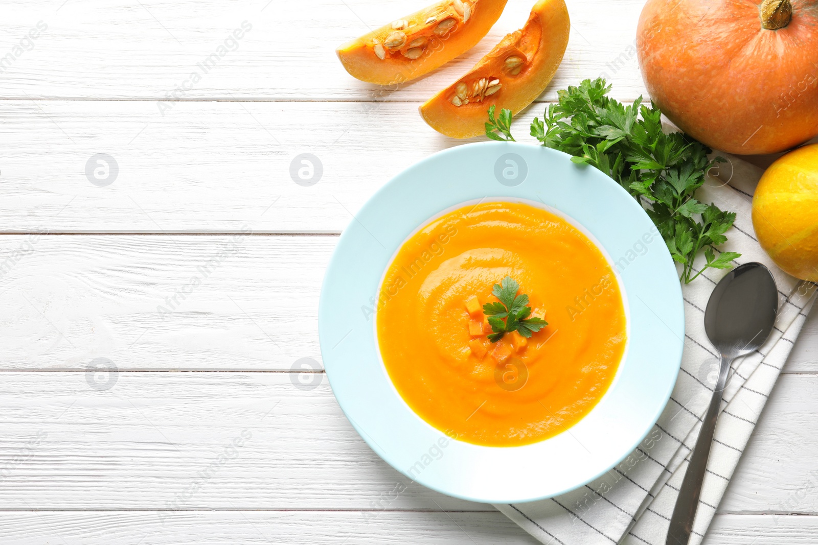 Photo of Flat lay composition with tasty pumpkin soup and space for text on wooden background