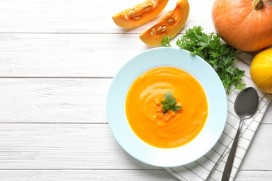Flat lay composition with tasty pumpkin soup and space for text on wooden background