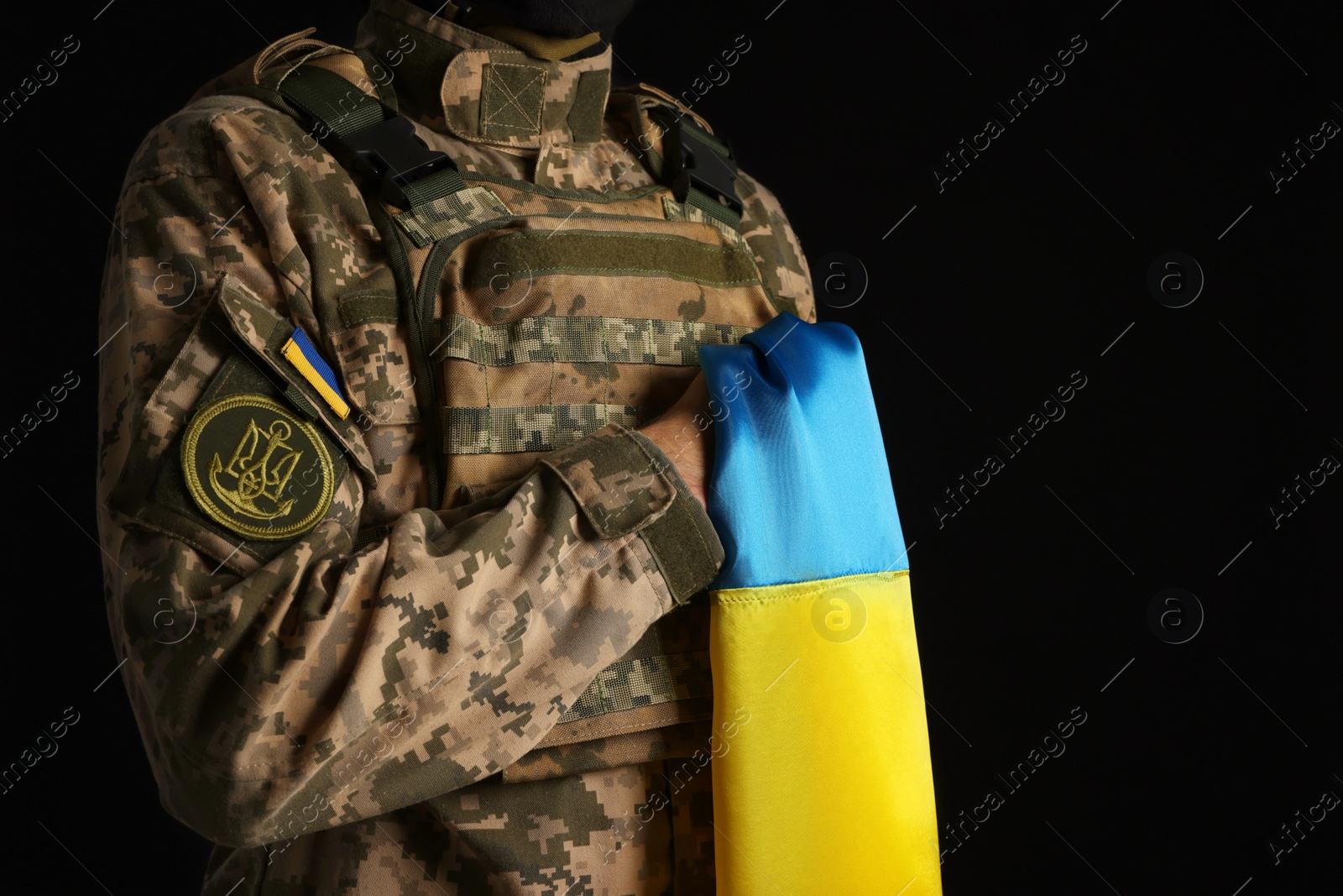 Photo of Soldier in military uniform with Ukrainian flag on black background, closeup