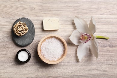 Flat lay composition with spa products and beautiful flower on light wooden table