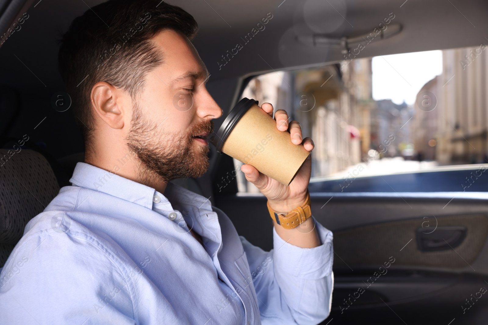 Photo of To-go drink. Handsome man drinking coffee in car, space for text