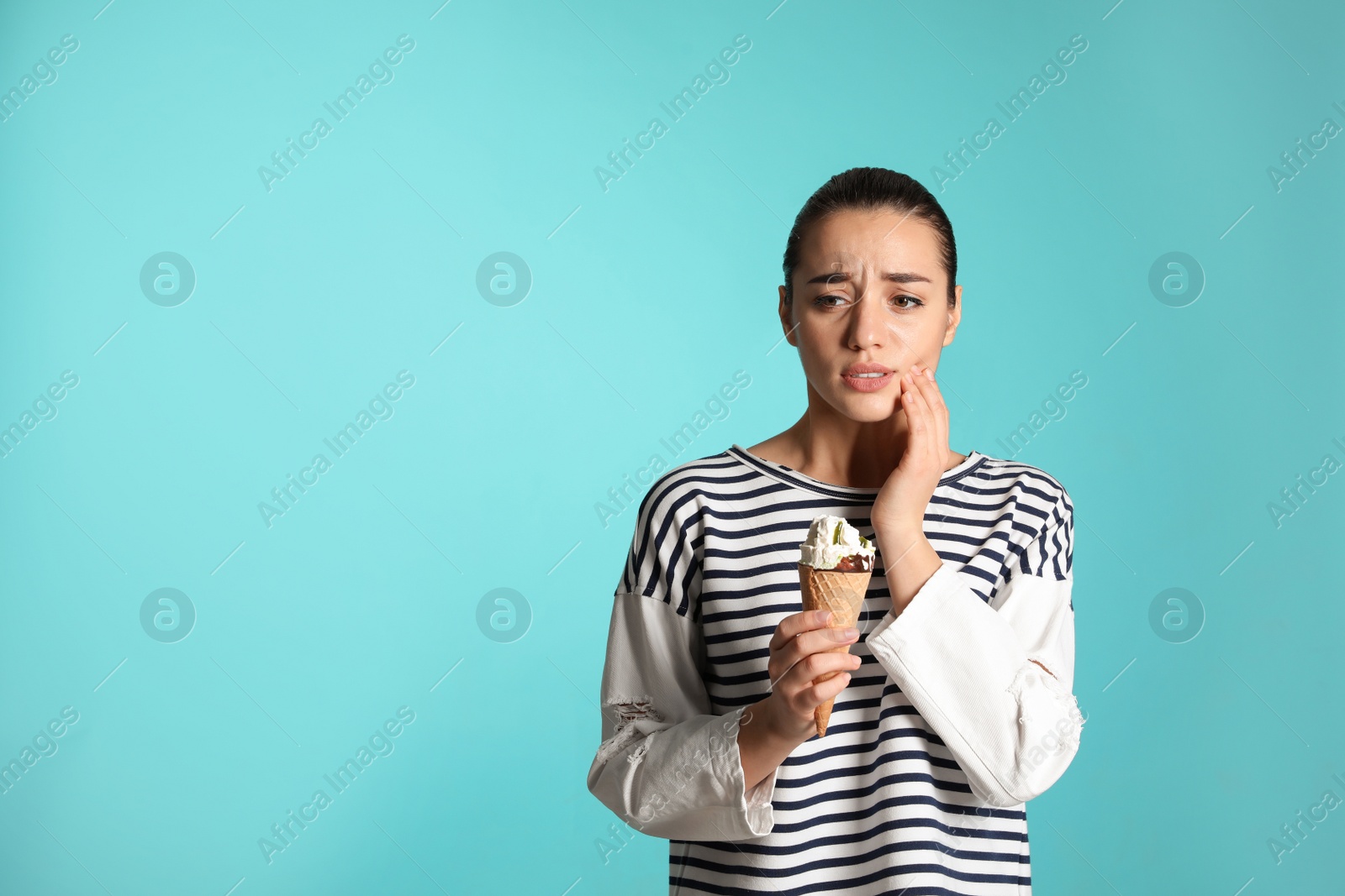 Photo of Emotional young woman with sensitive teeth and ice cream on color background. Space for text