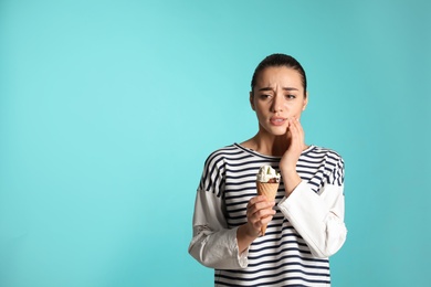 Photo of Emotional young woman with sensitive teeth and ice cream on color background. Space for text