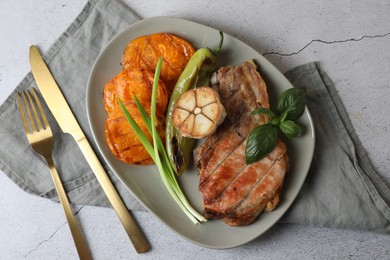 Delicious grilled meat and vegetables served on light grey table, flat lay