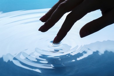 Photo of Woman touching clear water, closeup. Making ripples