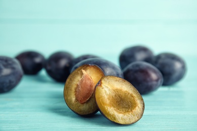 Delicious ripe plums on light blue wooden table, closeup. Space for text