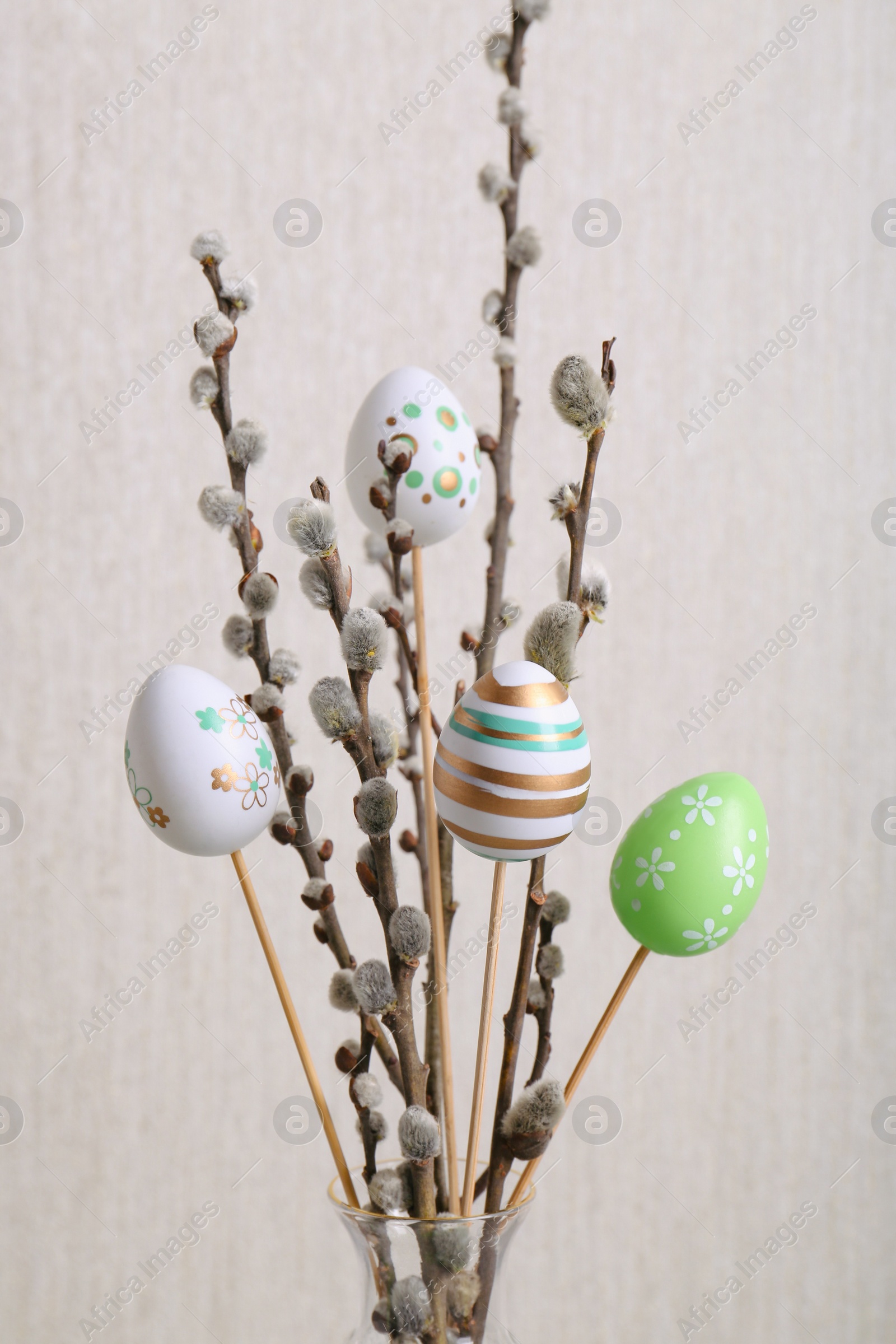 Photo of Beautiful willow branches with painted eggs on light grey background. Easter decor