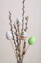 Photo of Beautiful willow branches with painted eggs on light grey background. Easter decor