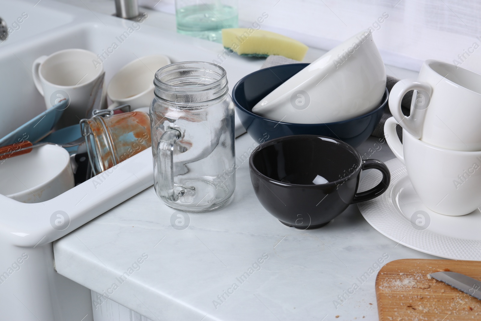 Photo of Many dirty utensils and dishware on countertop in messy kitchen