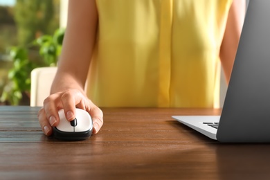 Photo of Woman using computer mouse with laptop at table, closeup