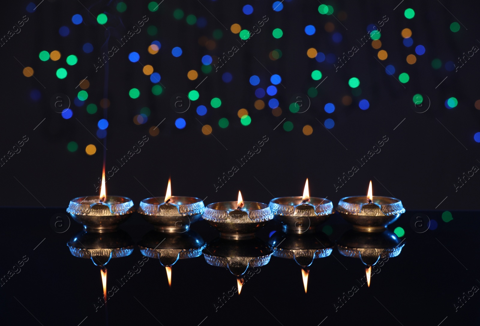 Photo of Many lit diyas on dark background with blurred lights, space for text. Diwali lamps