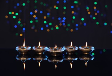 Many lit diyas on dark background with blurred lights, space for text. Diwali lamps