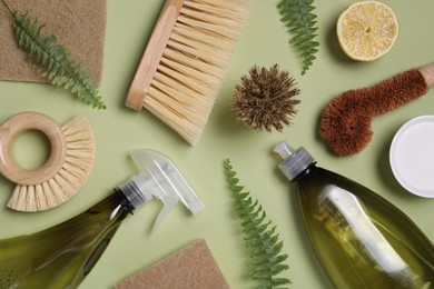 Photo of Flat lay composition with different cleaning supplies on green background