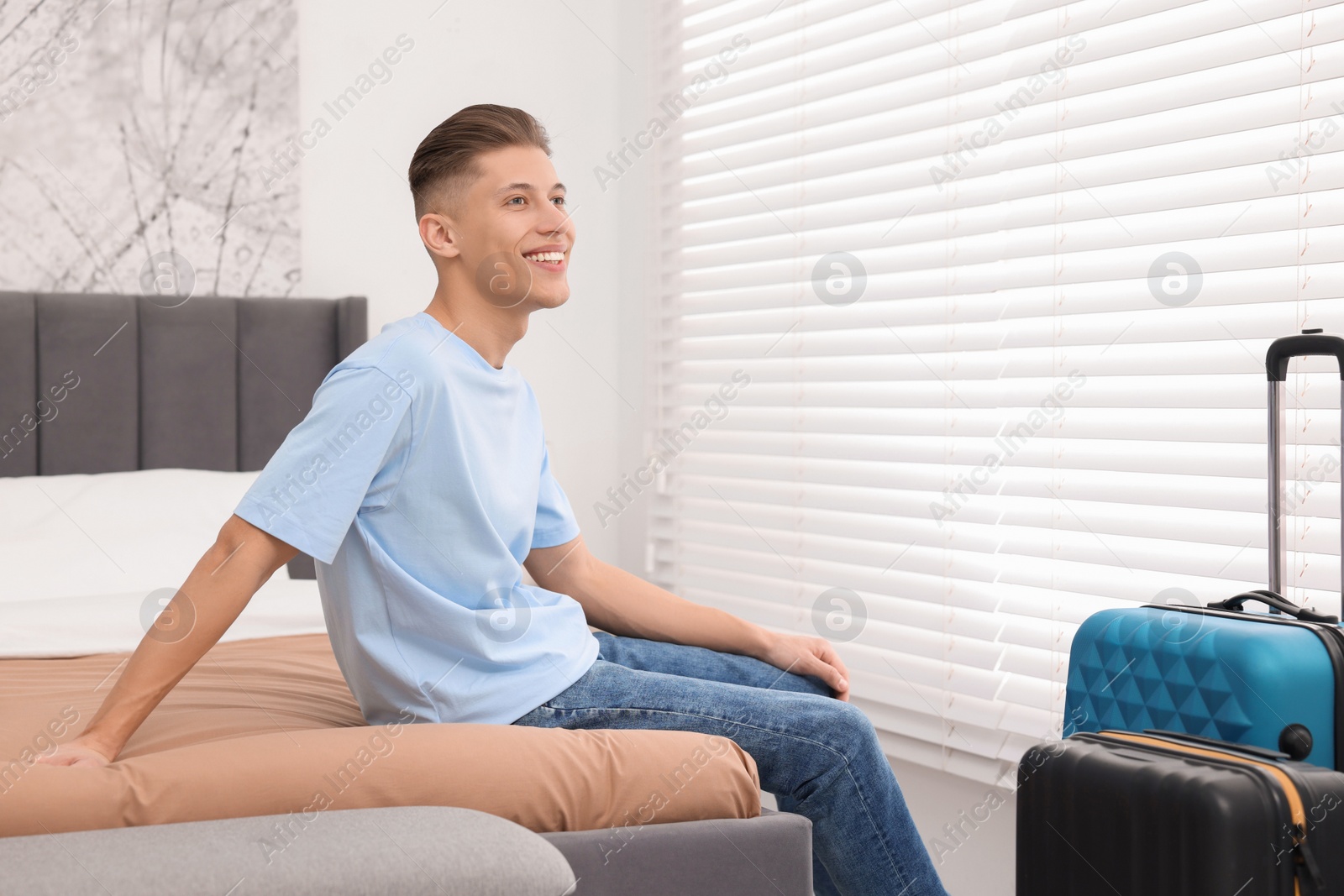 Photo of Smiling guest relaxing on bed in stylish hotel room