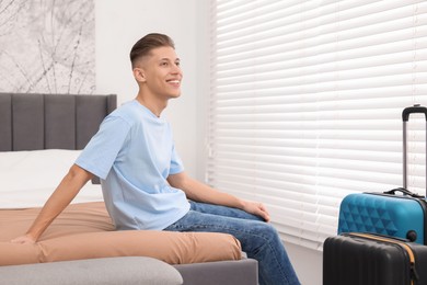 Smiling guest relaxing on bed in stylish hotel room