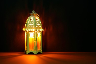 Decorative Arabic lantern on table against dark background. Space for text