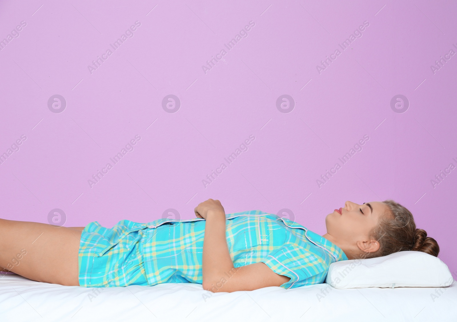 Photo of Beautiful woman sleeping with orthopedic pillow on bed against color background