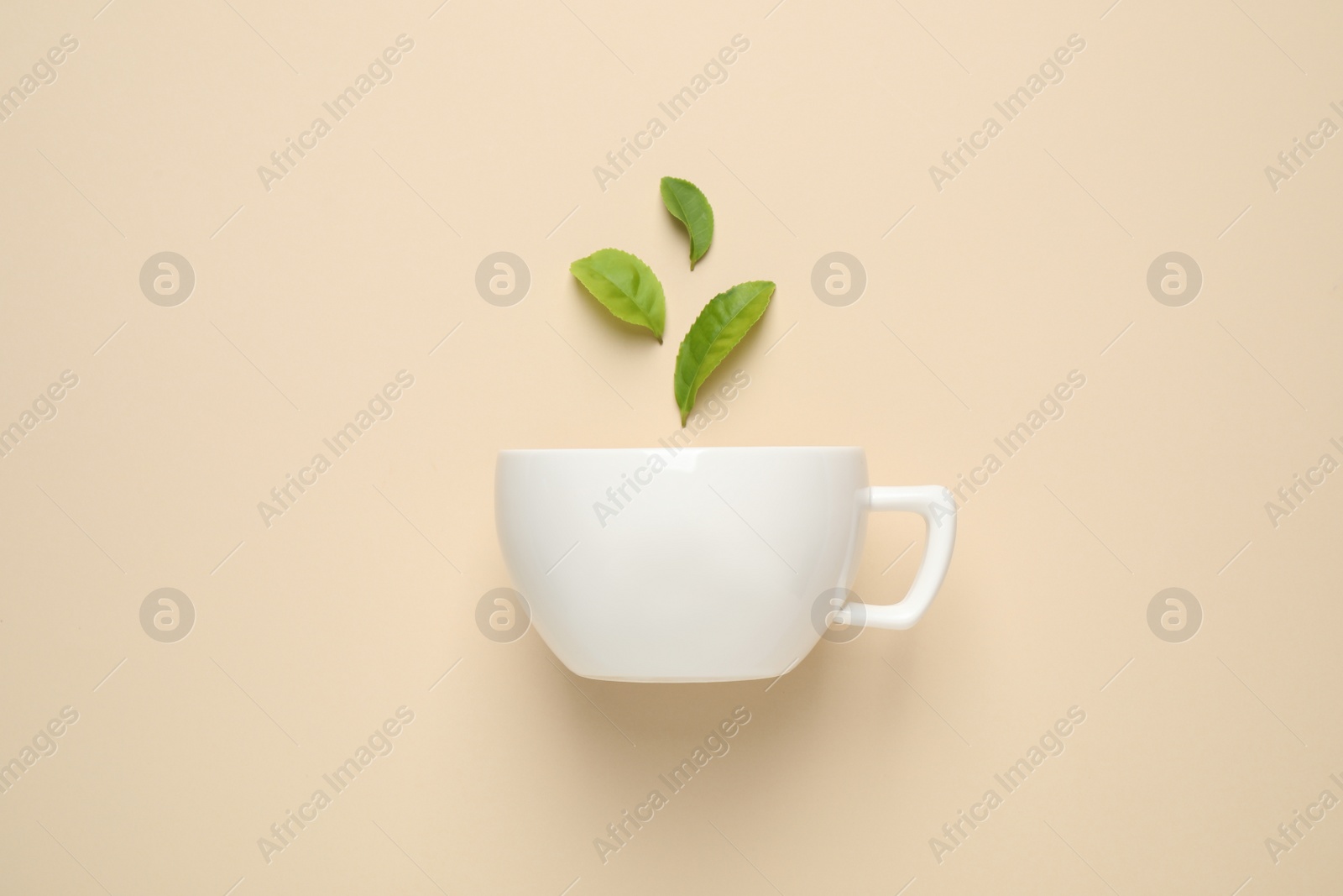 Photo of Fresh tea leaves and cup on beige background, top view