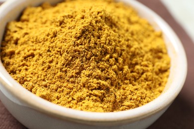 Photo of Curry powder in bowl on table, closeup