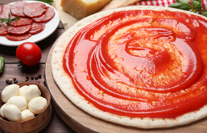 Photo of Base and fresh ingredients for pepperoni pizza on table, closeup
