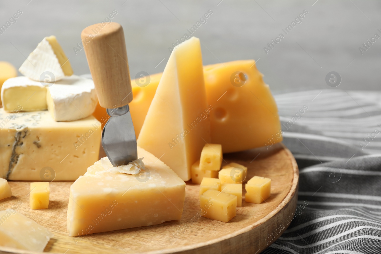 Photo of Different types of delicious cheese in wooden plate, closeup