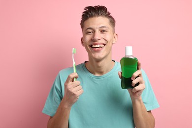 Photo of Young man with mouthwash and toothbrush on pink background