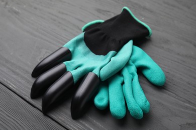Pair of claw gardening gloves on grey wooden table, closeup