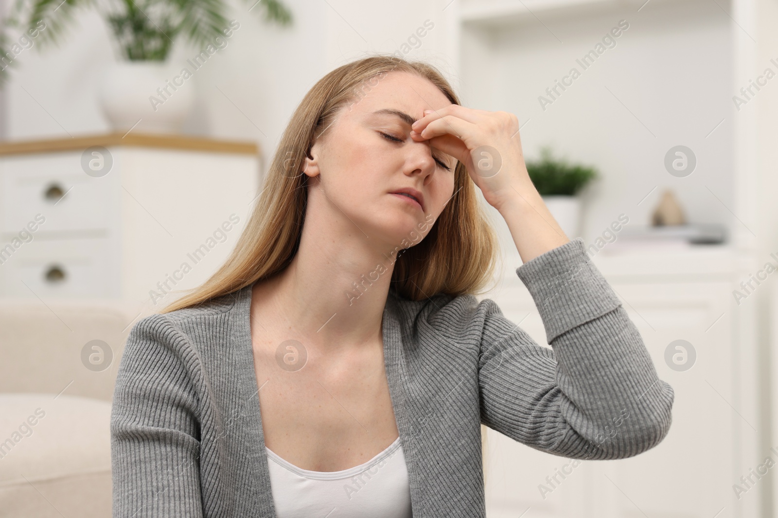 Photo of Overwhelmed young woman suffering from headache at home