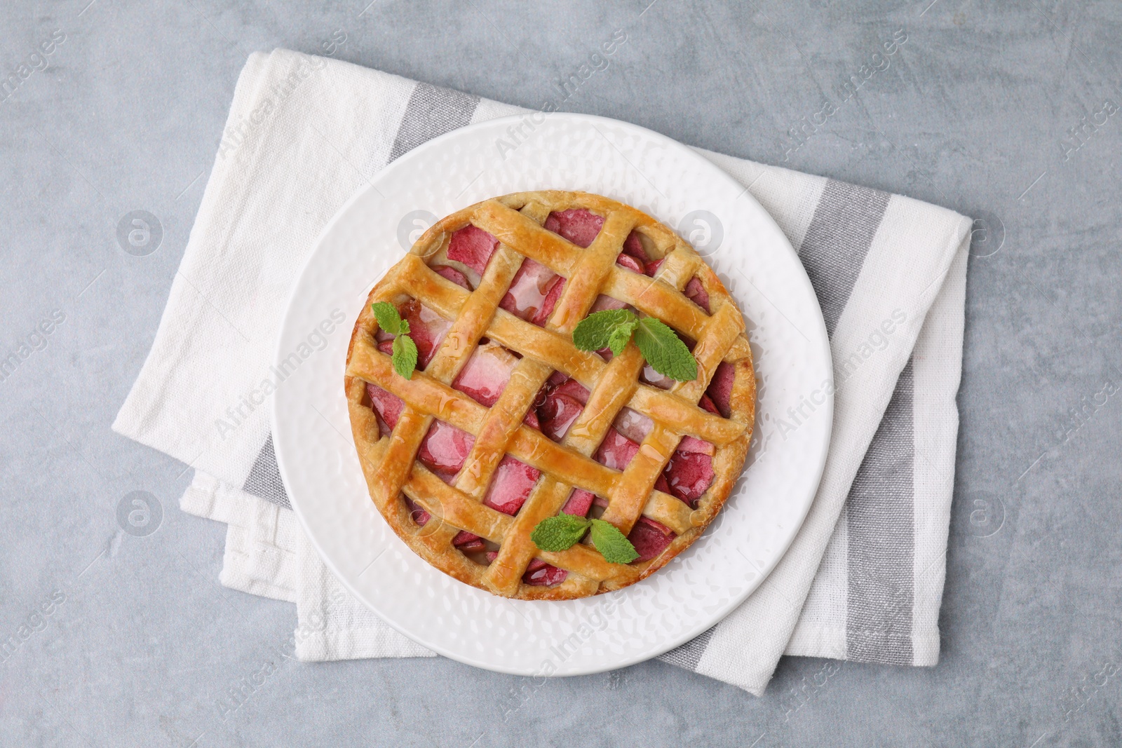 Photo of Delicious apple pie with mint on grey table, top view