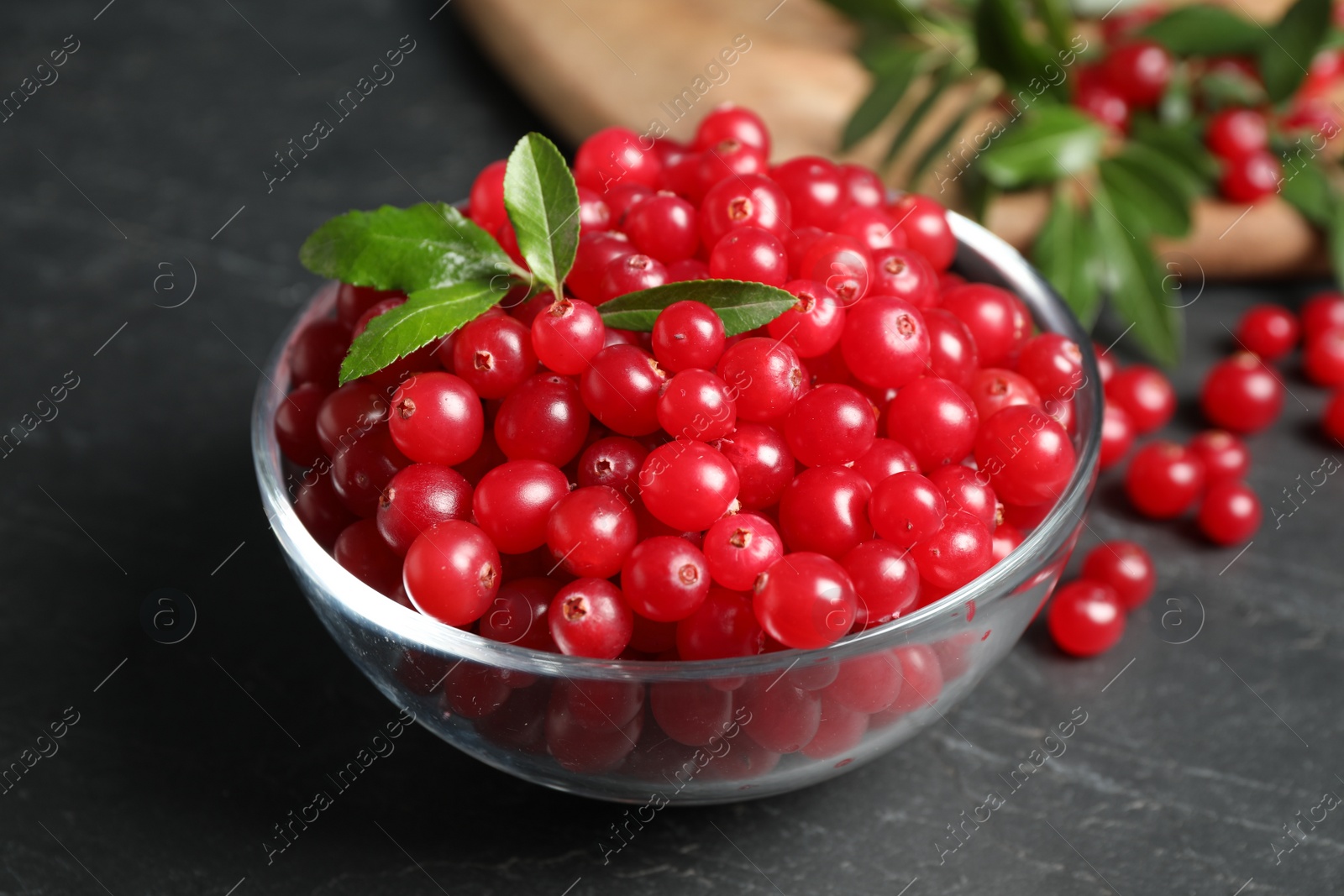 Photo of Fresh cranberry in bowl on dark grey table, closeup