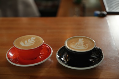Photo of Cups of coffee on wooden counter in bar. Space for text