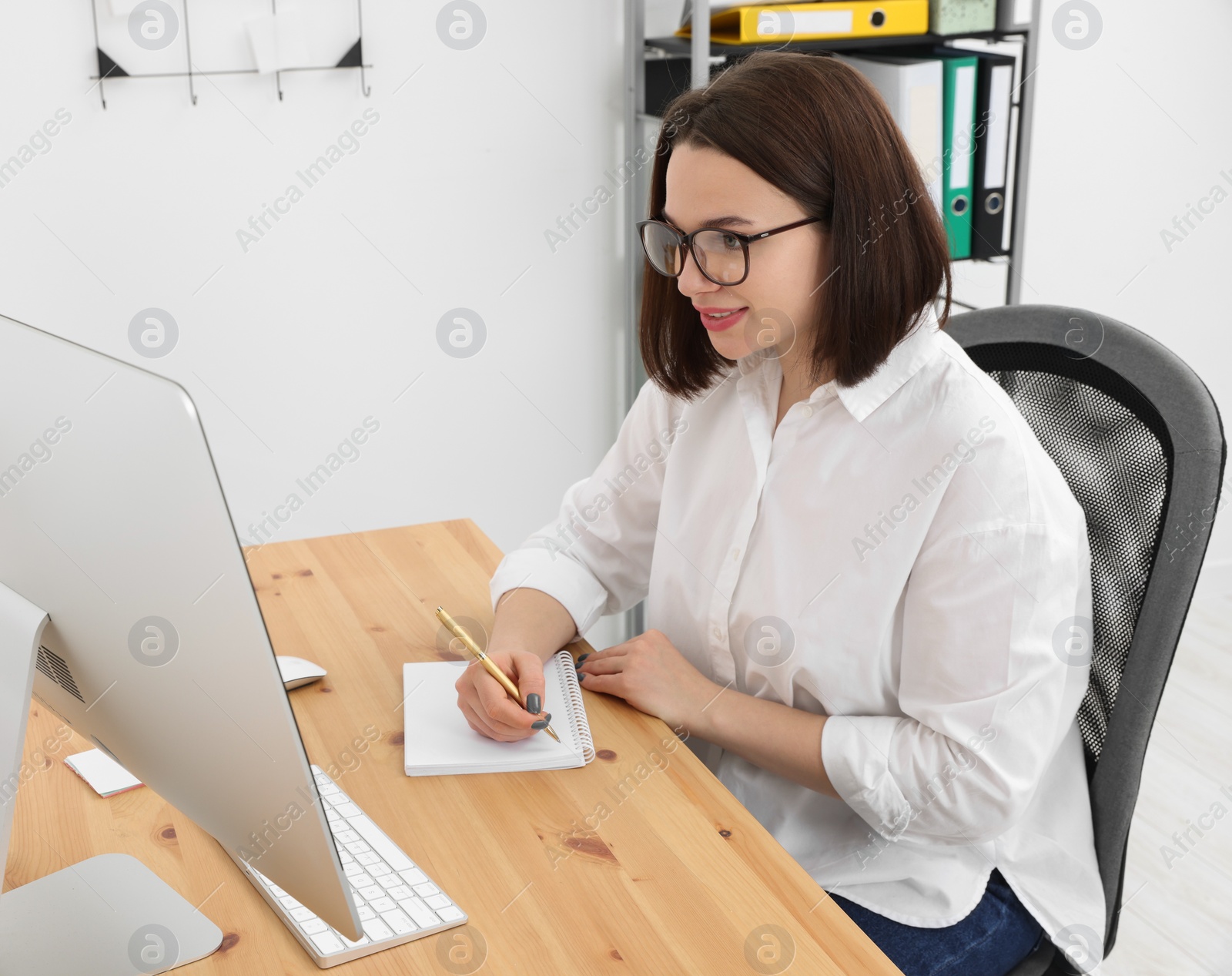 Photo of Happy young intern working at table in modern office